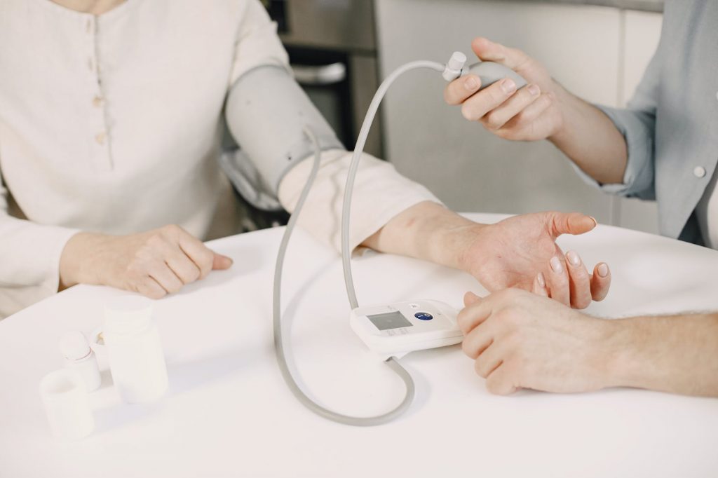 close up of man measuring blood pressure of a woman using a blood pressure monitor at home